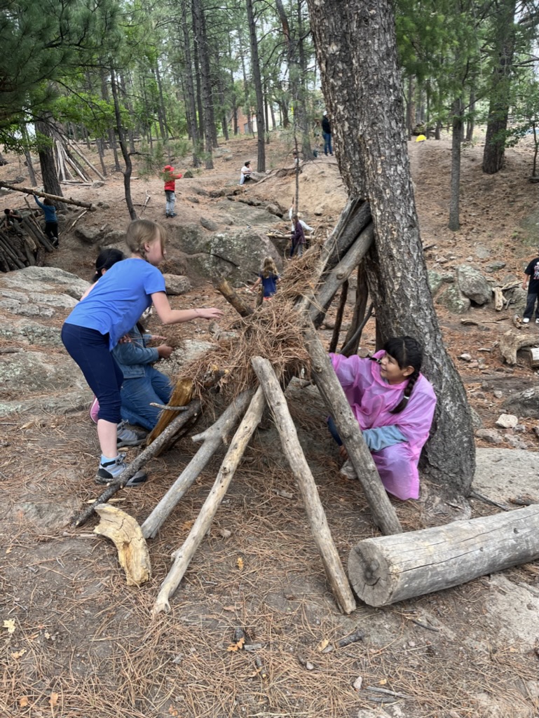 Children building a tree fort at the Pajarito Environmental Education Center