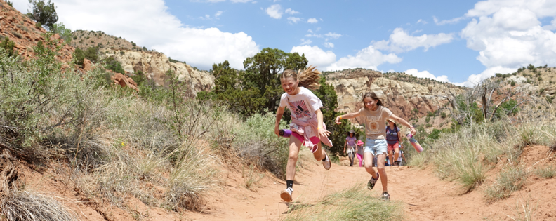 Two young kids running on a hiking trail. Pajarito Environmental Education Center