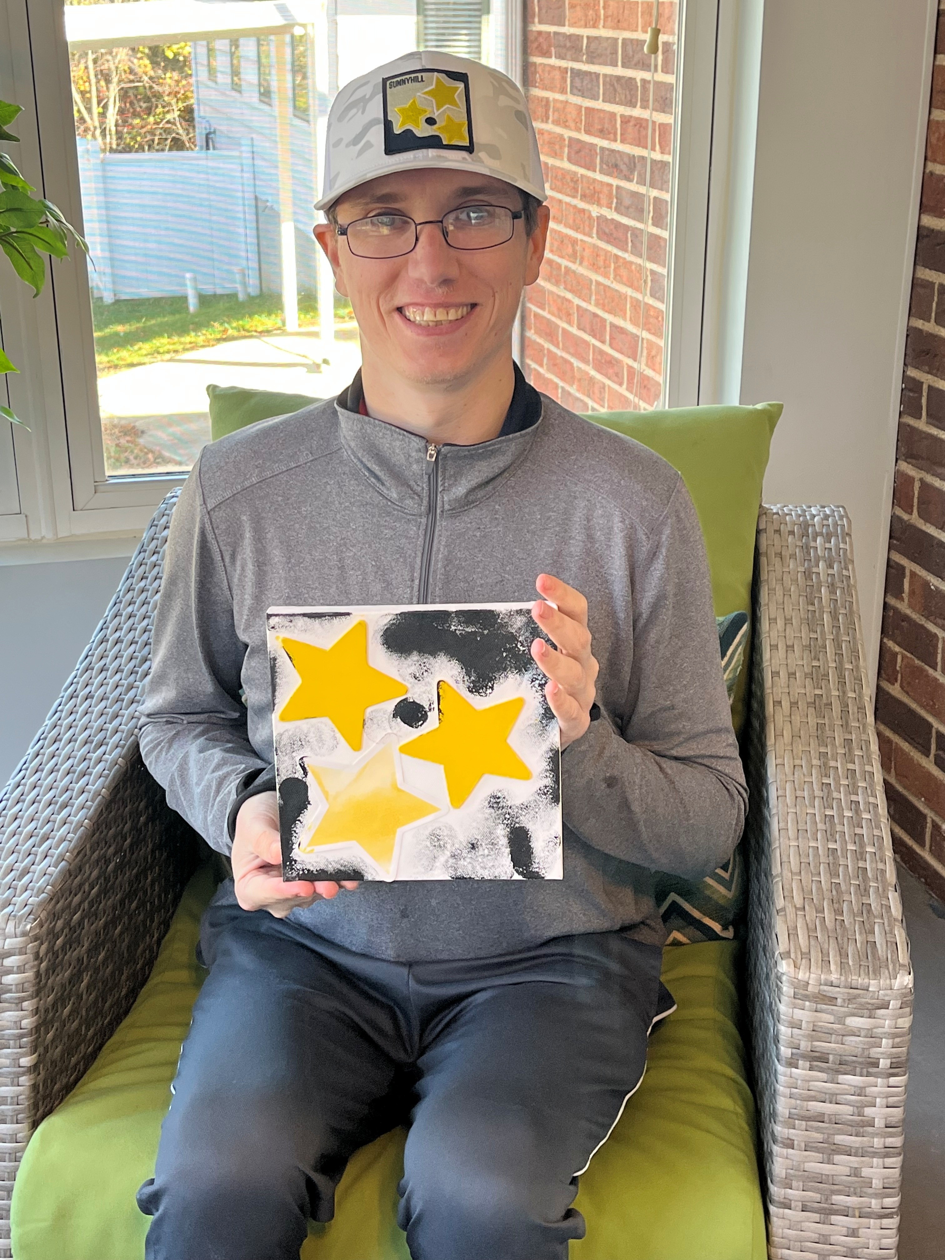 Teenage male holding a piece of artwork while smiling