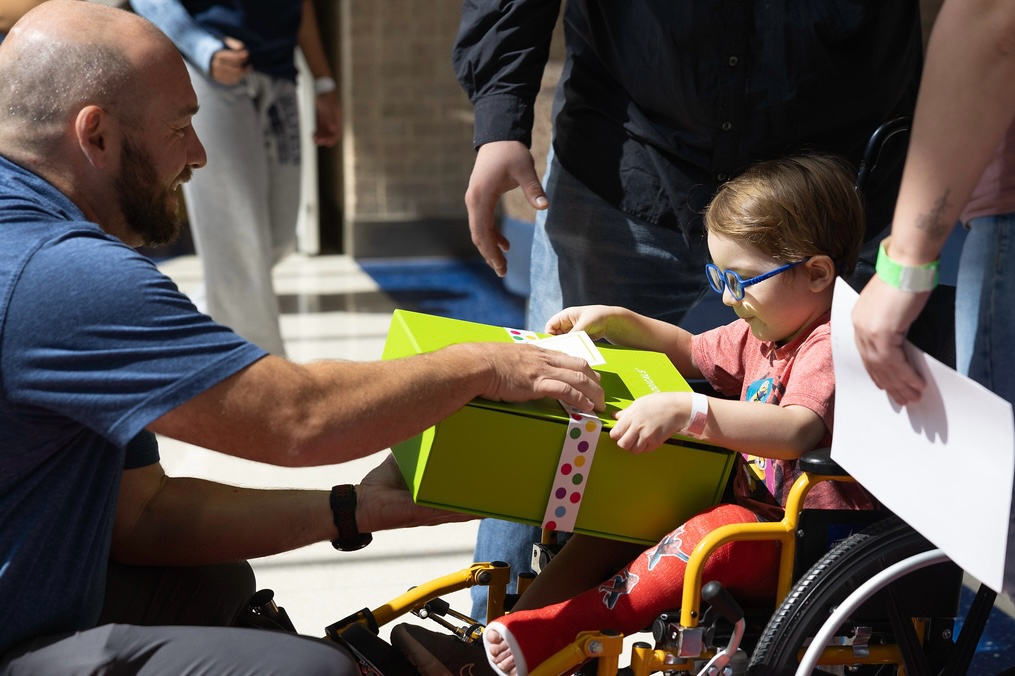 Cheeriodicals care packages, man hands present to child in wheelchair