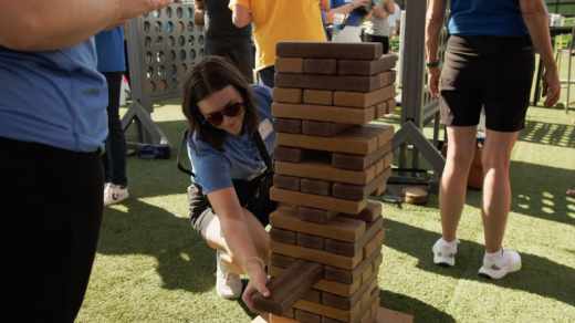 Woman playing a giant jenga set, 2024 community impact report