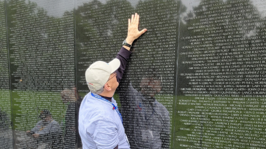 Man with his hand on a memorial wall, community impact report 2024