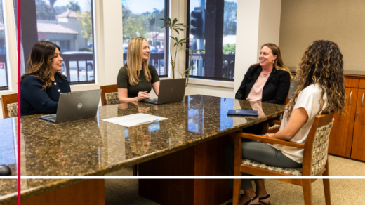 Four women sitting at a conference table having a discussion