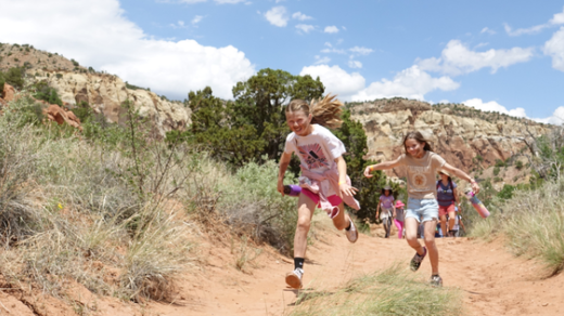 Two young kids running on a hiking trail