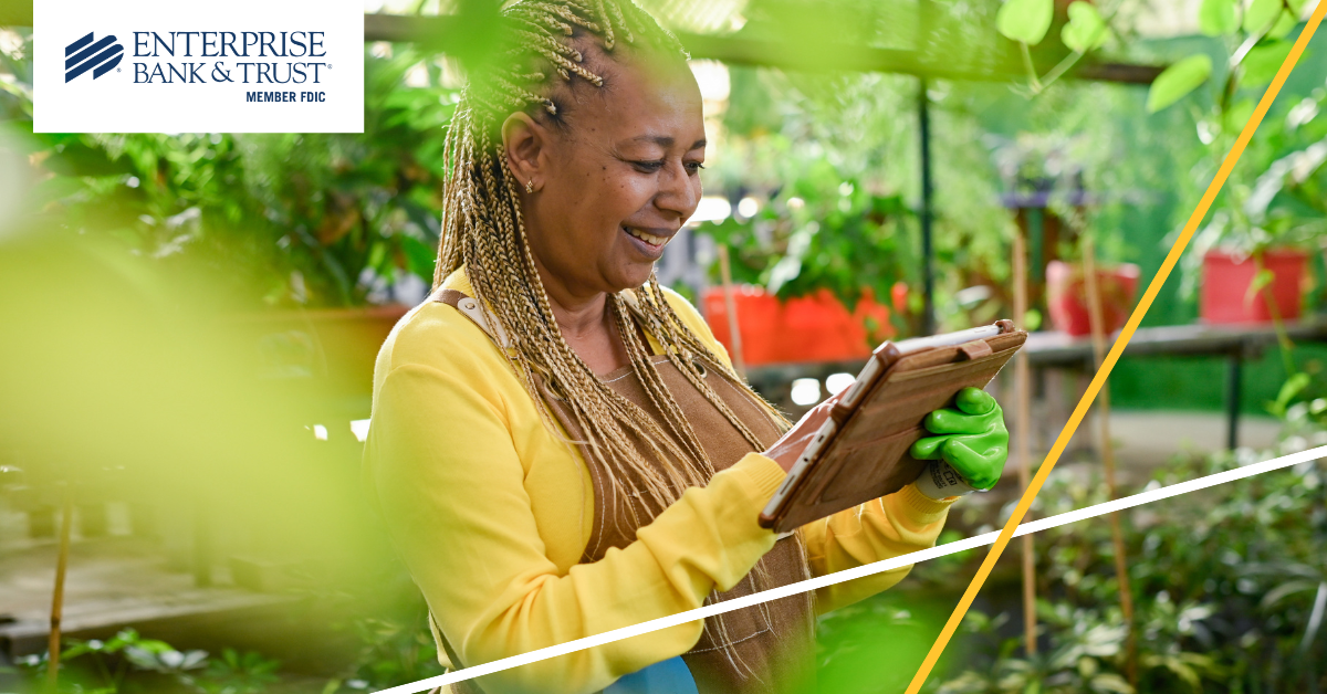 Woman in greenhouse viewing a computer tablet