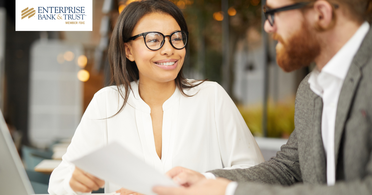 Enterprise Bank &amp; Trust logo and two young business professionals talking
