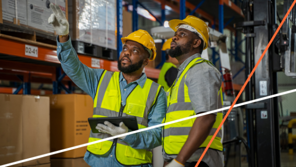 two men talking while standing in a warehouse