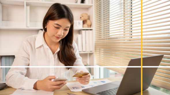Woman with a credit card in one hand and her phone in the other