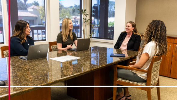 Four women sitting at a conference table having a discussion