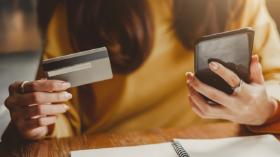 Woman holing a Credit Card in one hand and a phone in the other