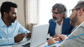 three men sitting at a table having a discussion