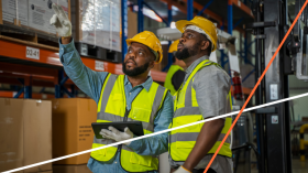 two men talking while standing in a warehouse