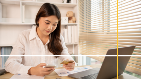 Woman with a credit card in one hand and her phone in the other