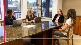 Four women sitting at a conference table having a discussion