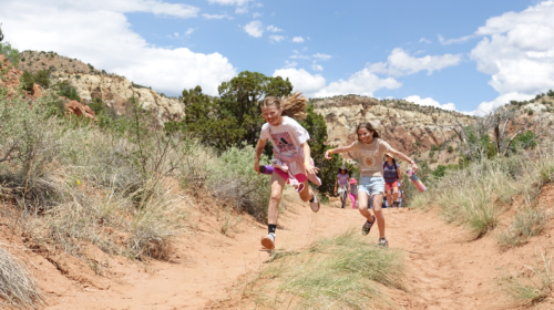 Two kids running on a hiking trail